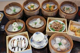 Assortment of dim sum and spring rolls artfully arranged on a bamboo tray.