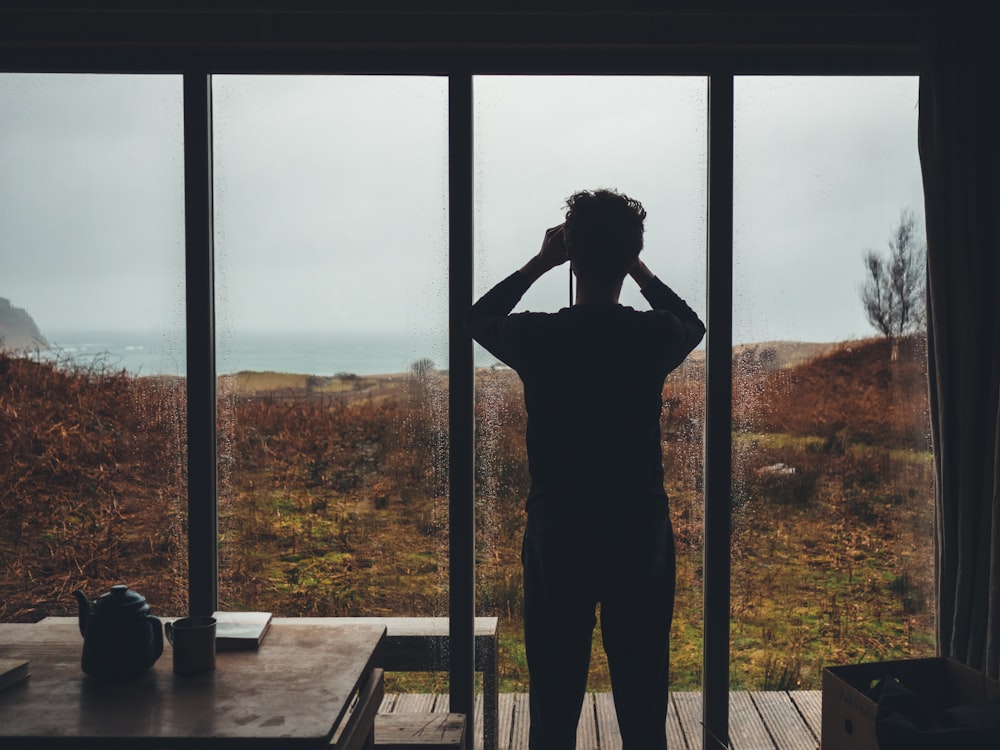 man standing near glass window