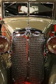 Close-up of a vintage car's polished chrome grille under soft lighting.