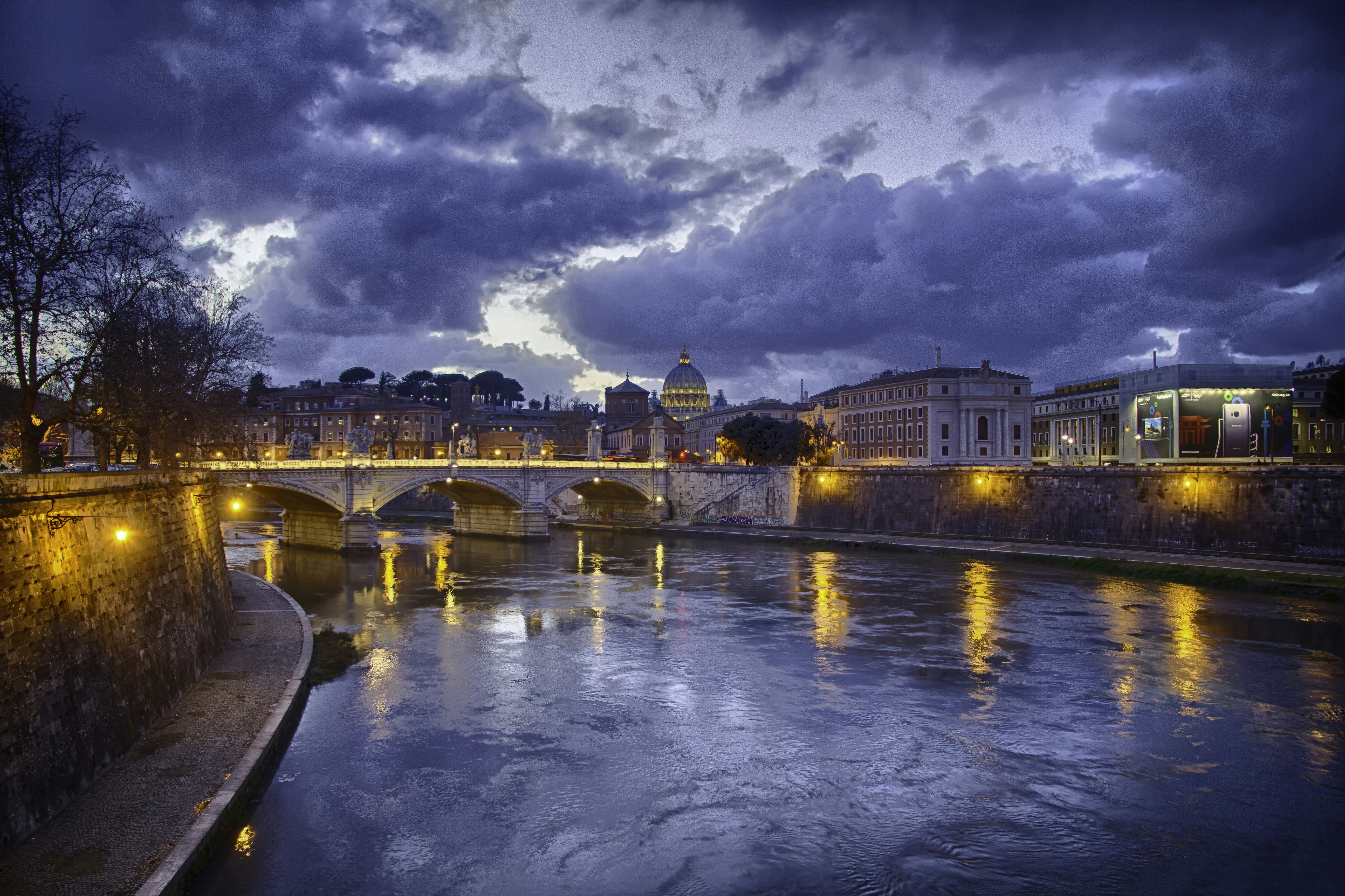 body of water near concrete bridge under cloudy sky, Ponte Vittoria Emanuelle II in it’s nightlighting is a beautiful bridge crossing the Tiber in Rome.</p><p>I saw the bridge with St. Peter’s church in the background and just wanted to freeze the moment in time. The only way to capture the beaty it deserved was by taking an HDR image.