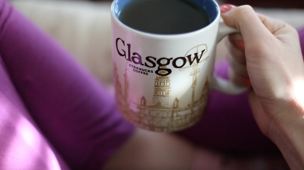 person holding ceramic mug with coffee inside