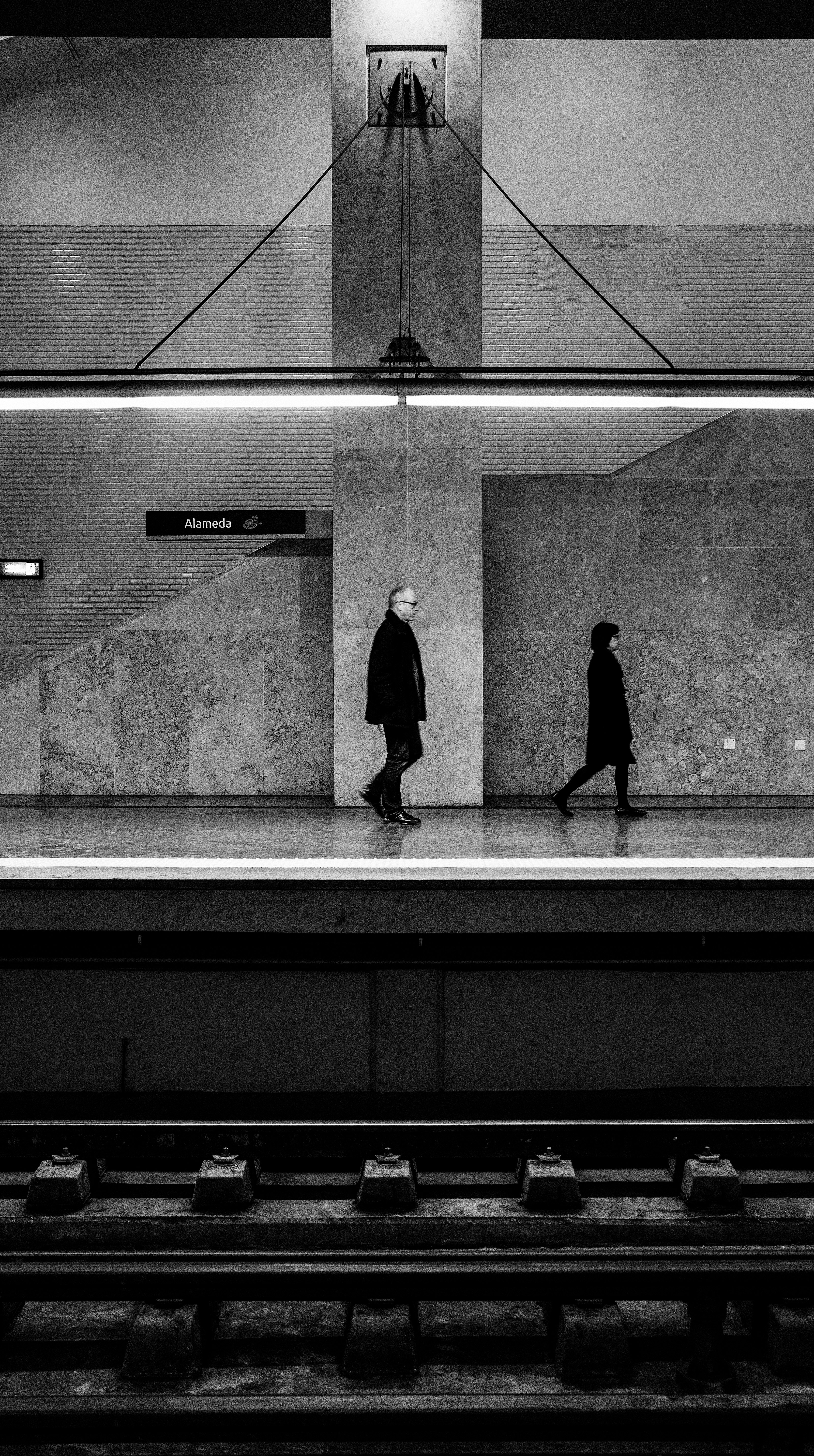 two person walking beside the train rail