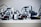 Several LEGO Mindstorms robots are lined up on a shelf with visible wires and sensor modules. Each robot has wheels and complex assemblies made from LEGO pieces, including sensors and connectors.