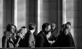 grayscale photography of men and women walking near wall