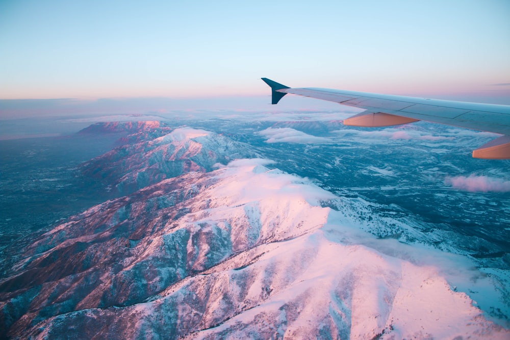 An airplane window with a view of the snow covered mountains photo – Fly  Image on Unsplash