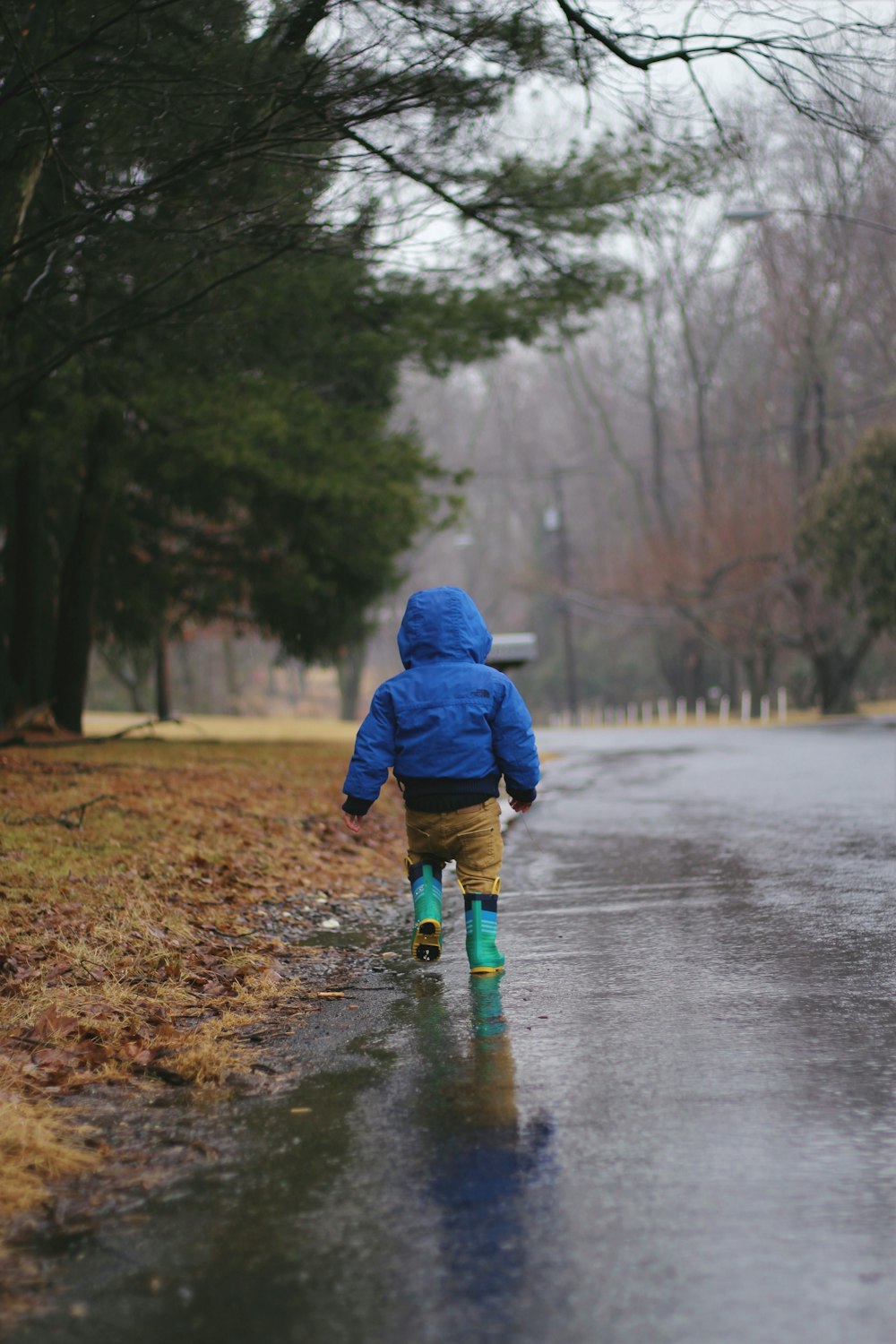 toddler walking on road while raining