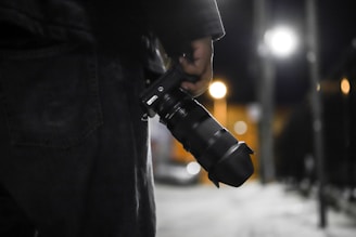 standing person holding DSLR camera during night