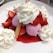 Scoops of pink ice cream topped with dollops of whipped cream and surrounded by fresh strawberries. A crispy wafer sticks out from one of the scoops. Strawberry syrup is poured over the dessert, pooling around the ice cream and fruit.