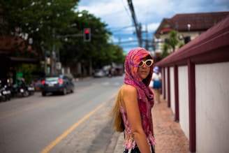 woman walking on the street near white and purple wall