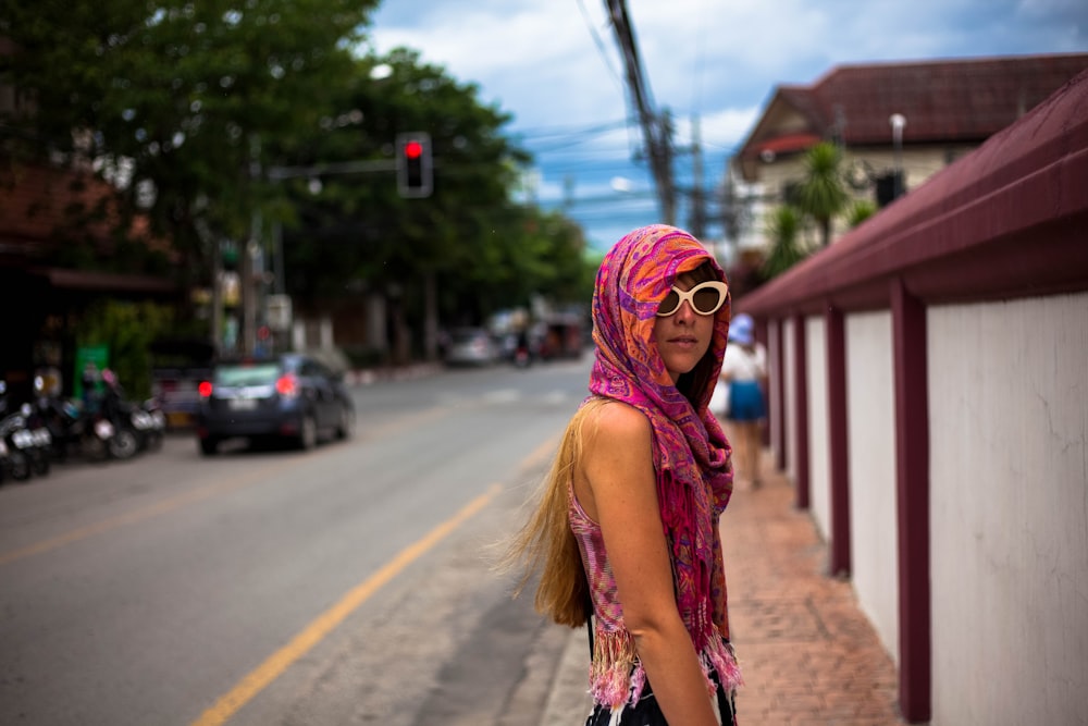 Mulher que caminha na rua perto da parede branca e roxa