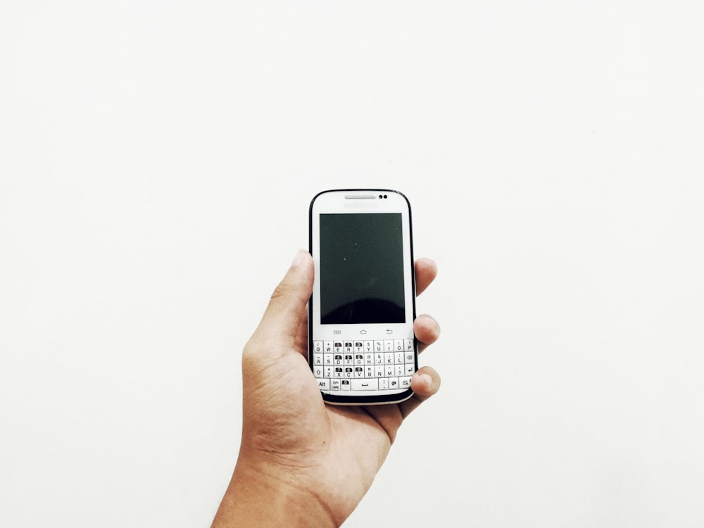 person holding white QWERTY phone