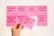 A set of pink sticky notes arranged on a wall with various handwritten tasks related to usability and customer interaction. A hand is holding one sticky note in the foreground with the writing 'RUN A USABILITY TEST'.
