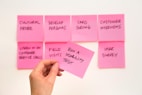 person holding pink sticky note