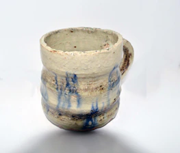 Close-up of a hand-thrown stoneware mug with turquoise glaze and personalized engraving.