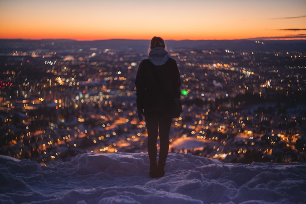 person standing on mountain looking on lights