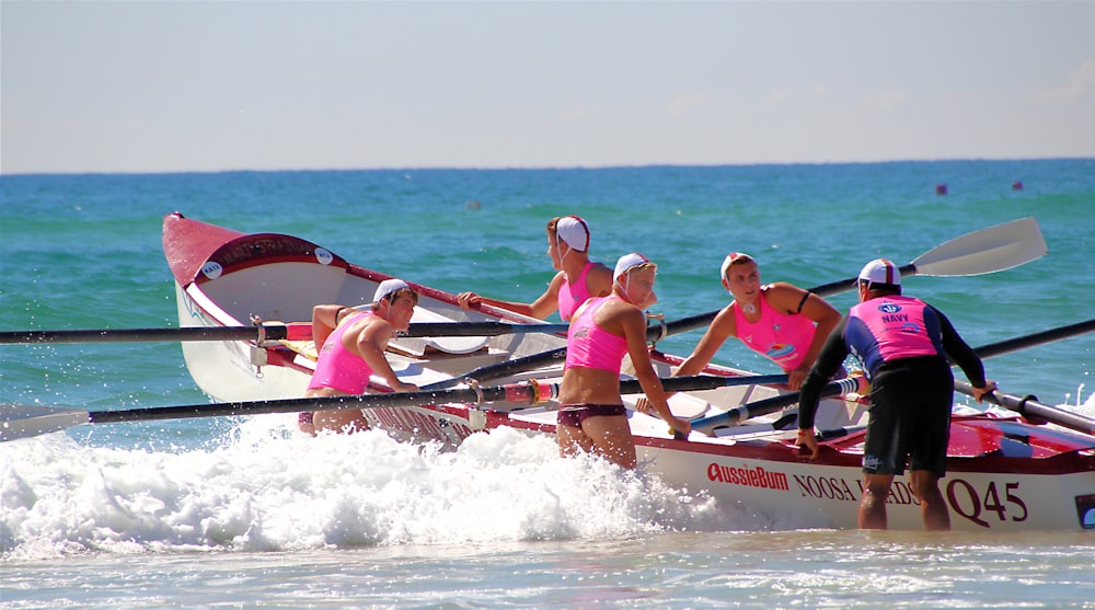 five women wearing pink crop tops about to ride on boat