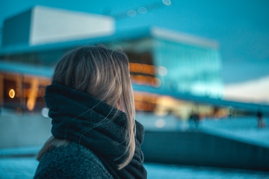 woman standing near building under dark cloudy sky in Oslo Opera House Norway