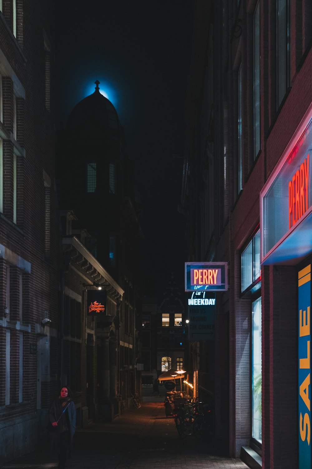 woman walking between buildings during nigttime