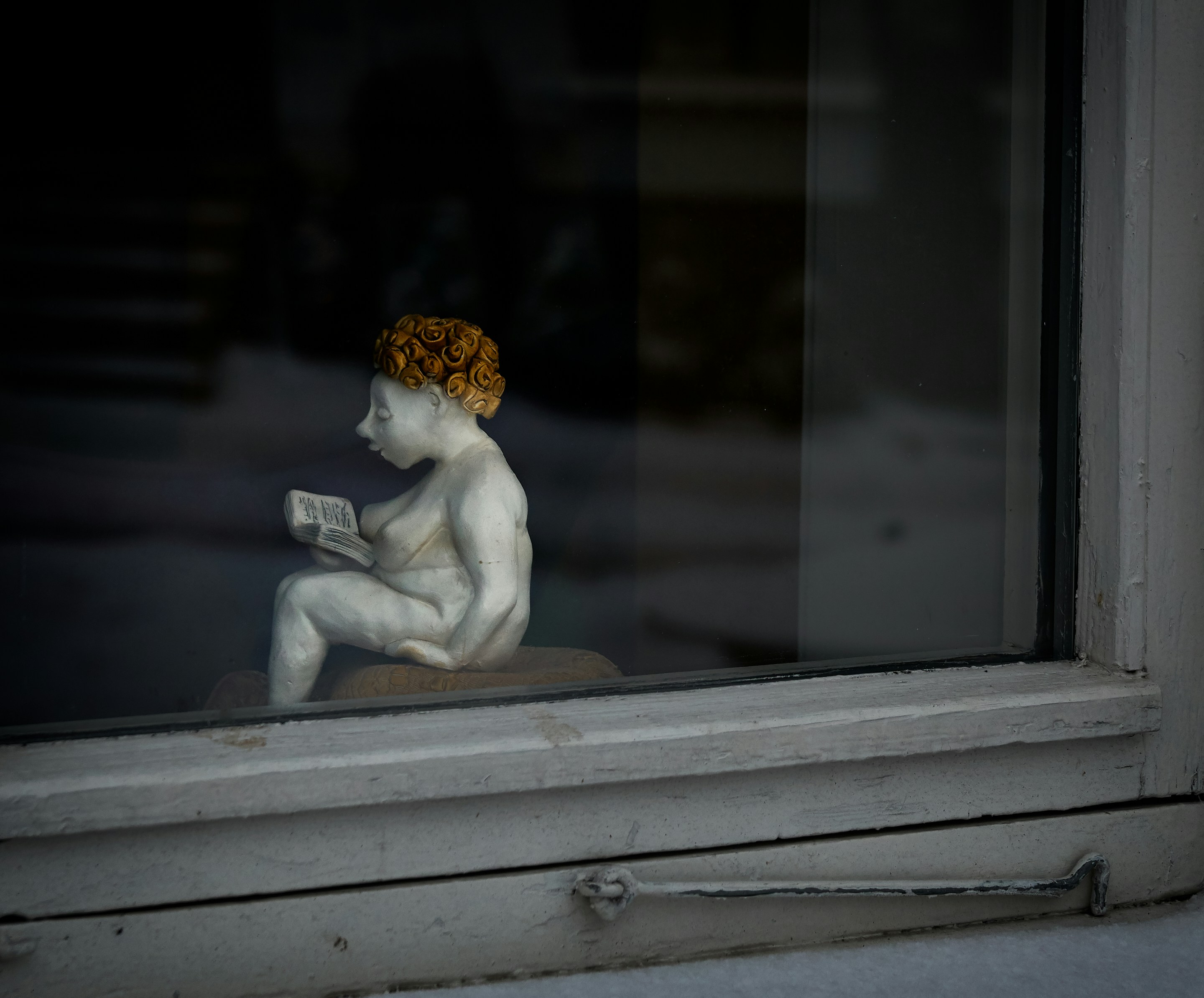 woman reading book figurine by the window