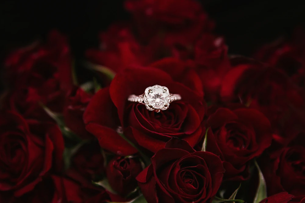 A diamond ring resting on a dark surface, catching the light