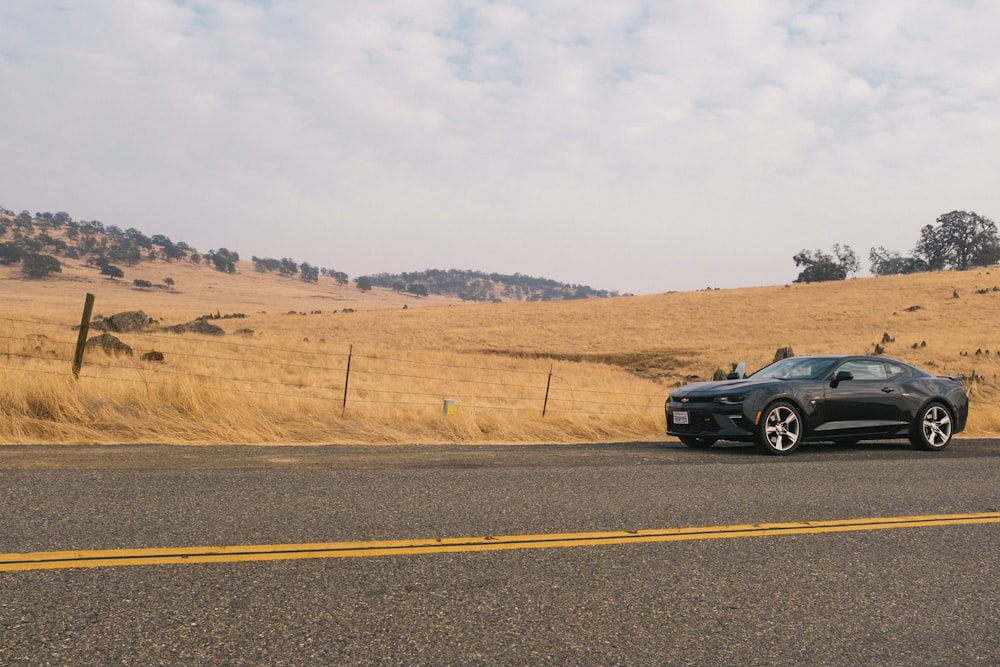 black coupe on road beside grass field