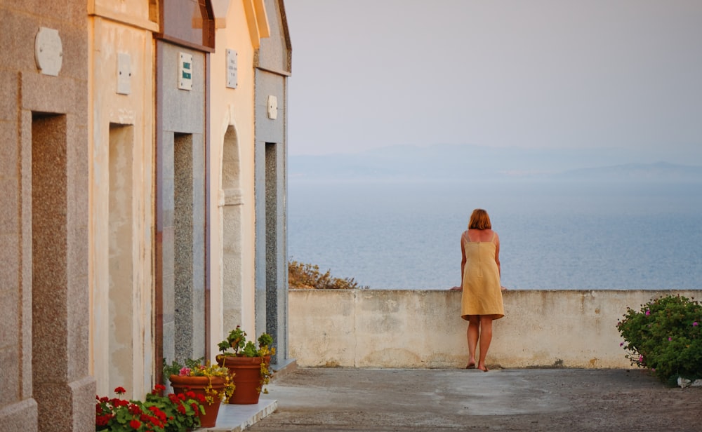 a woman in a yellow dress looking out over the ocean