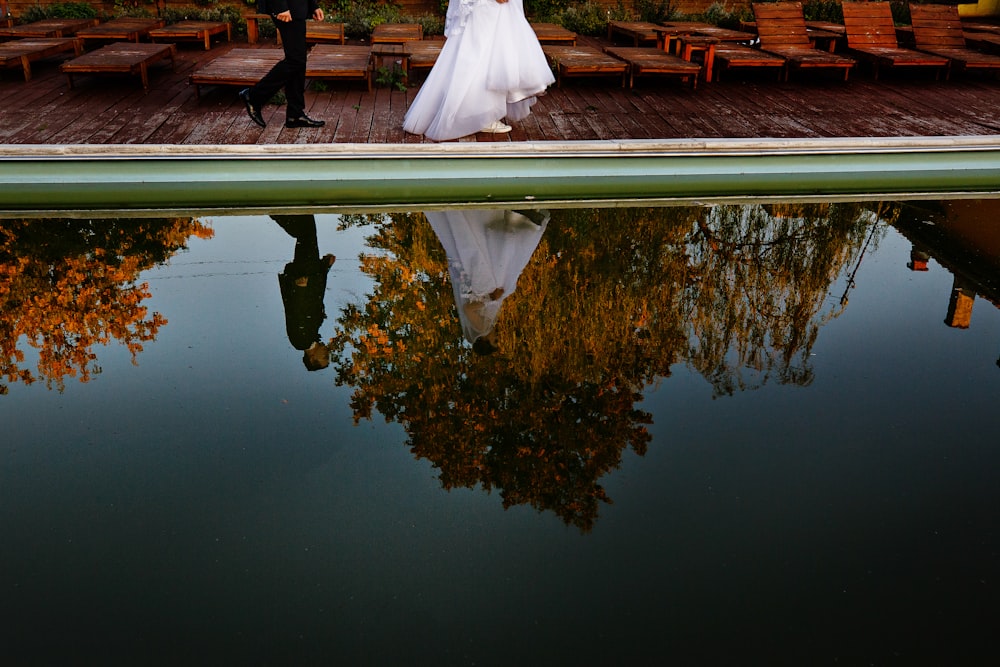 woman and man walking towards dock beside body of water