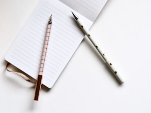 two white and beige pens on white paper