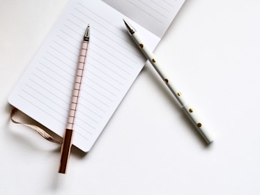 two white and beige pens on white paper