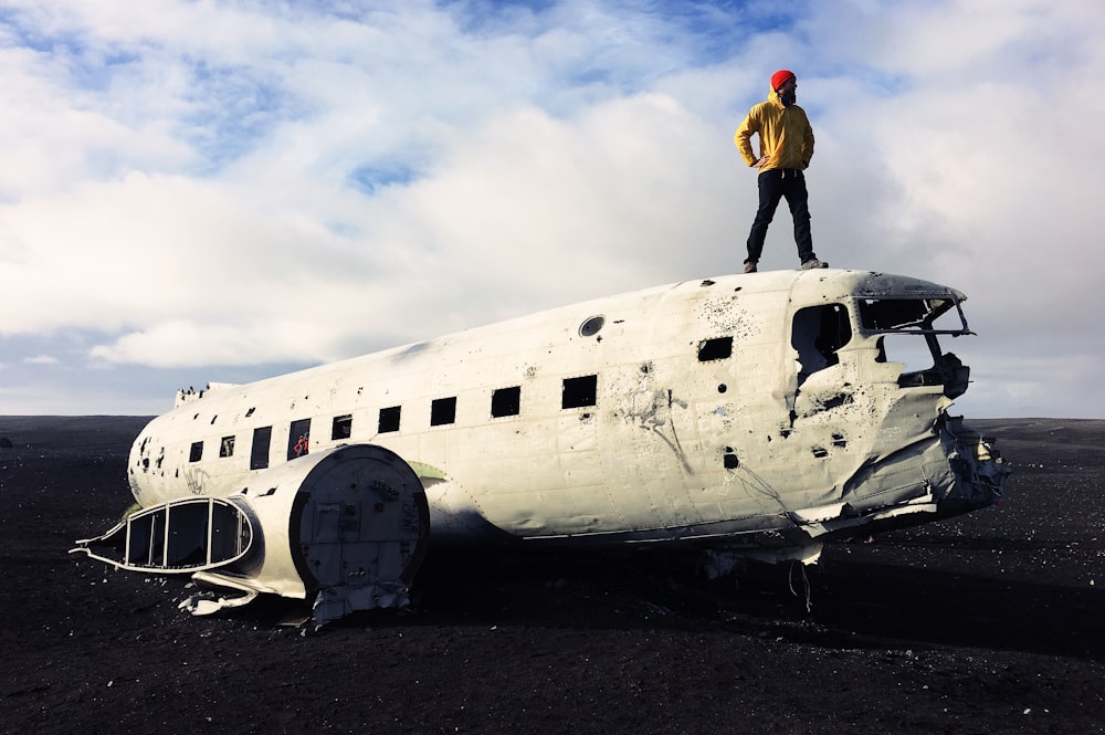 man standing on white abandoned plane under white sky