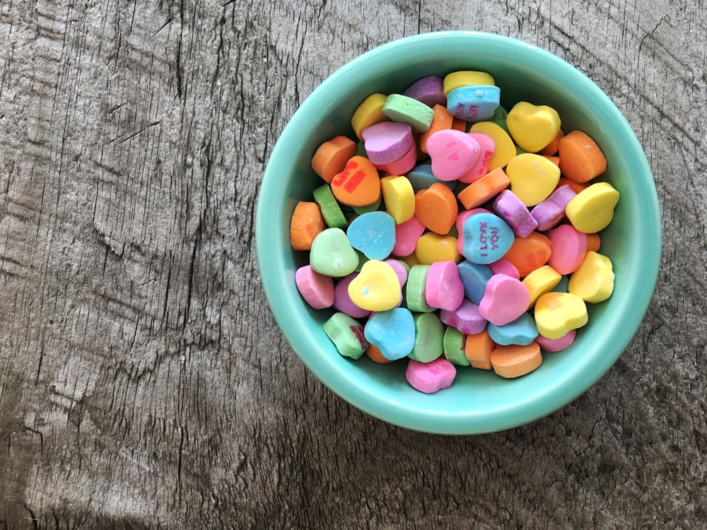 Caramelos en forma de corazón de colores variados en un cuenco verde azulado