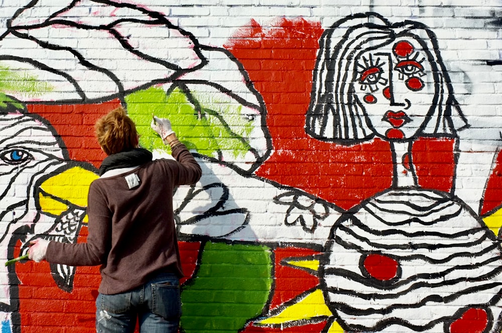 man painting on white wall during daytime