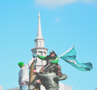 man in green shirt and brown pants holding green flag statue