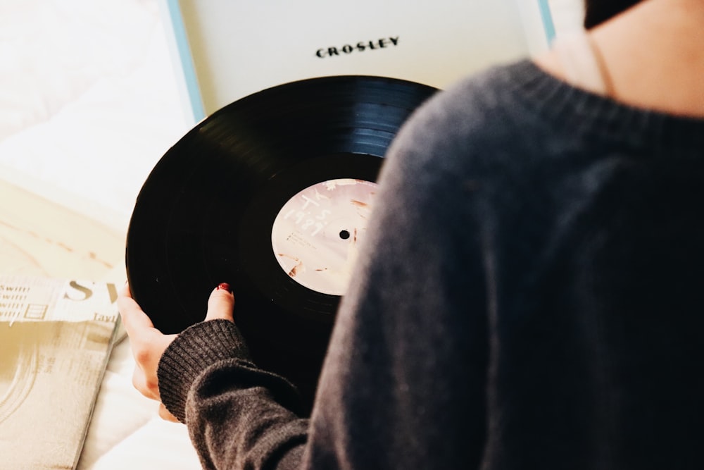 pessoa segurando disco de vinil preto