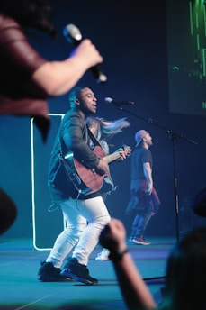 A group of young musicians performing freestyle rap in a dimly lit urban setting with neon lights.