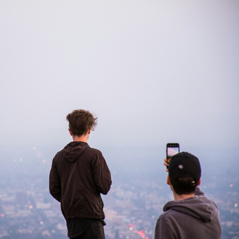 man taking a photo of a city during fog
