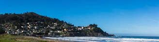A serene coastal town view with charming houses and clear blue sea under a sunny sky.