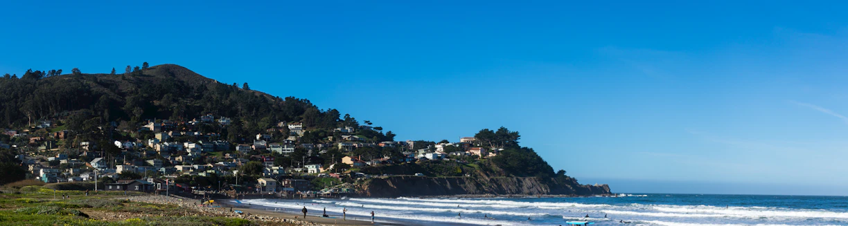 A serene coastal town view with charming houses and clear blue sea under a sunny sky.