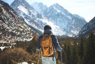man holding pair of ski poles in front of trees