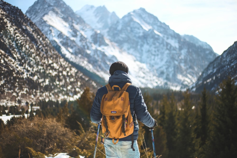 man holding pair of ski poles in front of trees