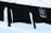 Black long-sleeve shirts are hanging on a clothesline against a bright, partly cloudy sky. One shirt features a design with arrows and the phrase 'Stand With Standing Rock'.