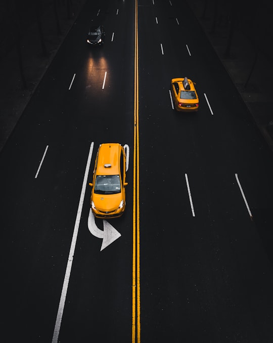 yellow SUV on road with left turn sign in Manhattan United States