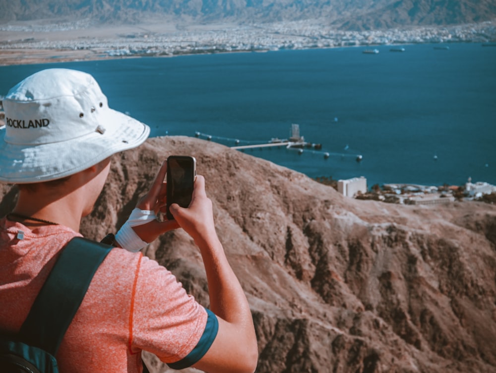 person taking picture on body of water and city