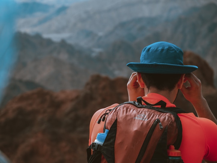 A hiker adjusting their GPS device on a rocky mountain trail at sunrise.