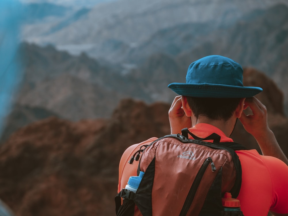 uomo che indossa zaino di fronte alle montagne durante il giorno