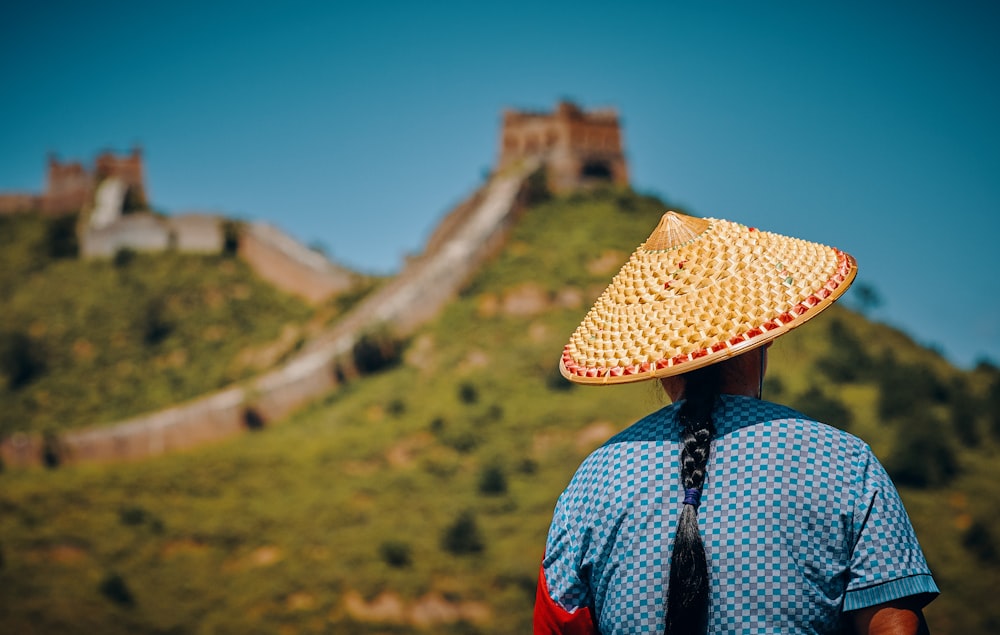 mulher usando chapéu de frente para a Grande Muralha da China