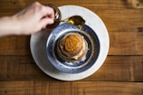 A wooden spoon drizzling syrup over pancakes.