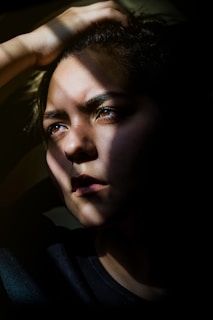 a depressed woman is holding her hair in the dark