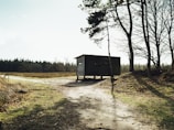 A rustic shelter framed with timber and covered with tarp, captured during sunset.