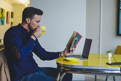 person reading book while drinking beverage reading google meet background